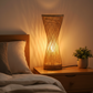 Lampe de chevet bambou bohème diffusant une lumière chaude sur table de nuit dans une chambre adulte moderne