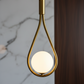 Lampe de chevet suspendue en laiton doré, style moderne et design pour chambre à coucher.